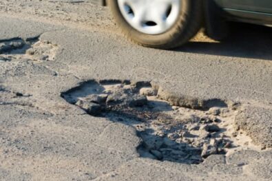 car driving past potholes