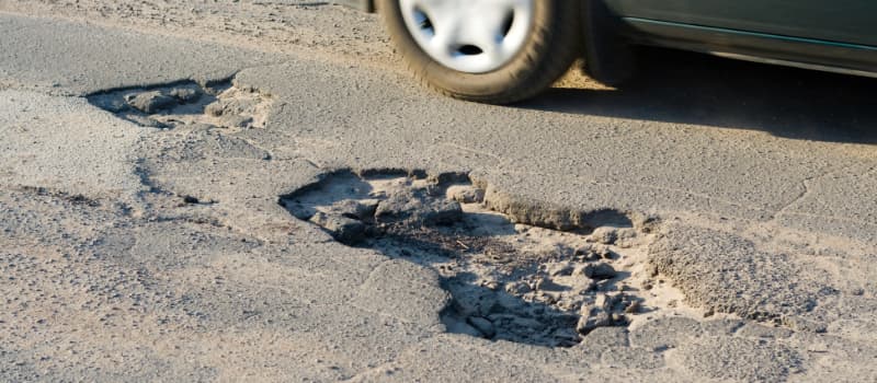 car driving past potholes