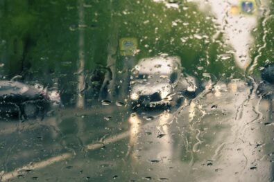 Car traffic through glass on rainy wet road