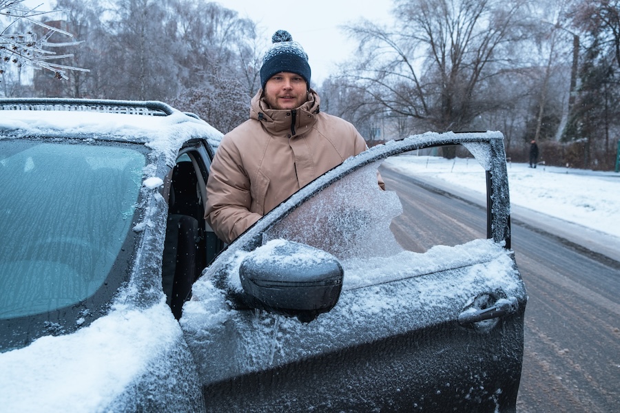 man near frozen car after night blizzard snowstorm