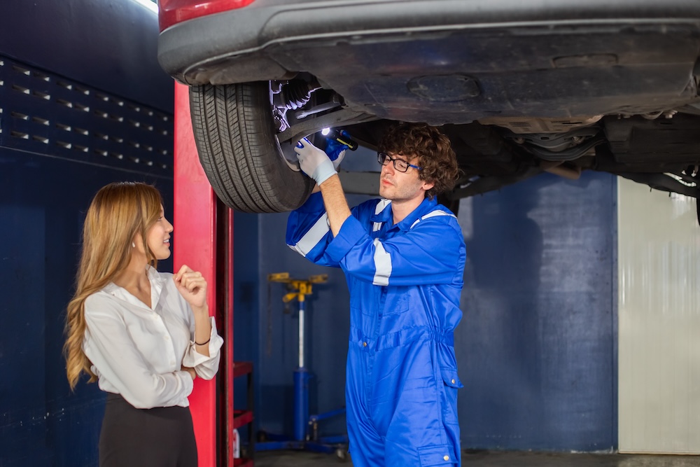 Mechanic conducts MOT test with woman customer watching